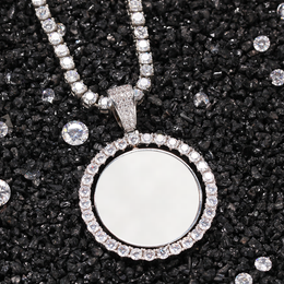 Silver-tone photo pendant with a white photo area on dark gravel beside loose faceted stones