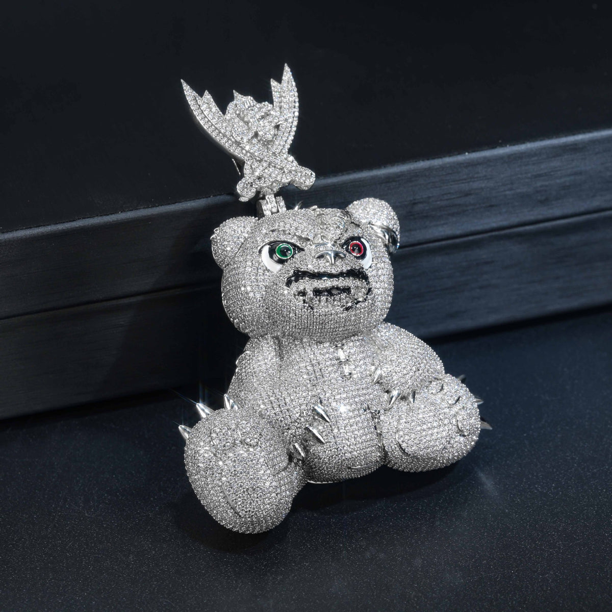Silver-tone pavé bear pendant resting upright on a dark surface