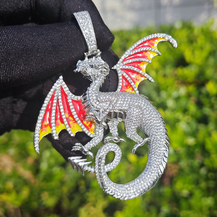 Silver-tone dragon pendant held by a black glove, showing the stone-set body