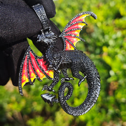 Black dragon pendant with red-and-yellow wing panels held by a black glove