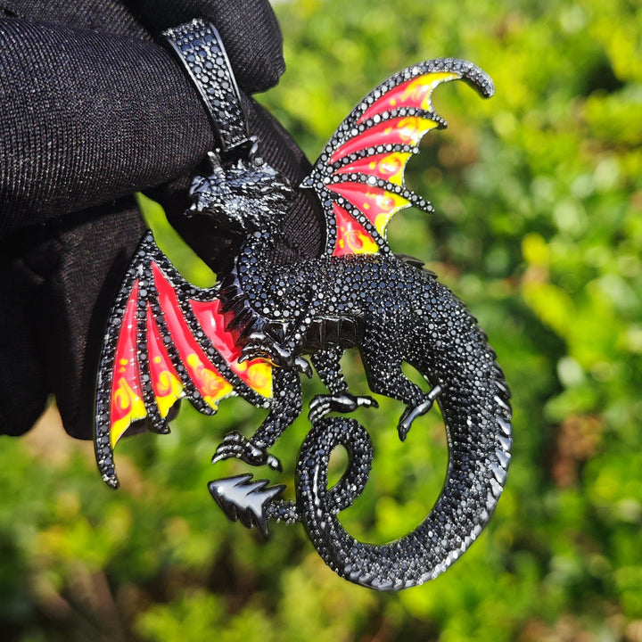 Black dragon pendant with red-and-yellow wing panels held by a black glove