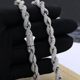 Close view of silver-tone rope links and a closed box clasp held against a black glove
