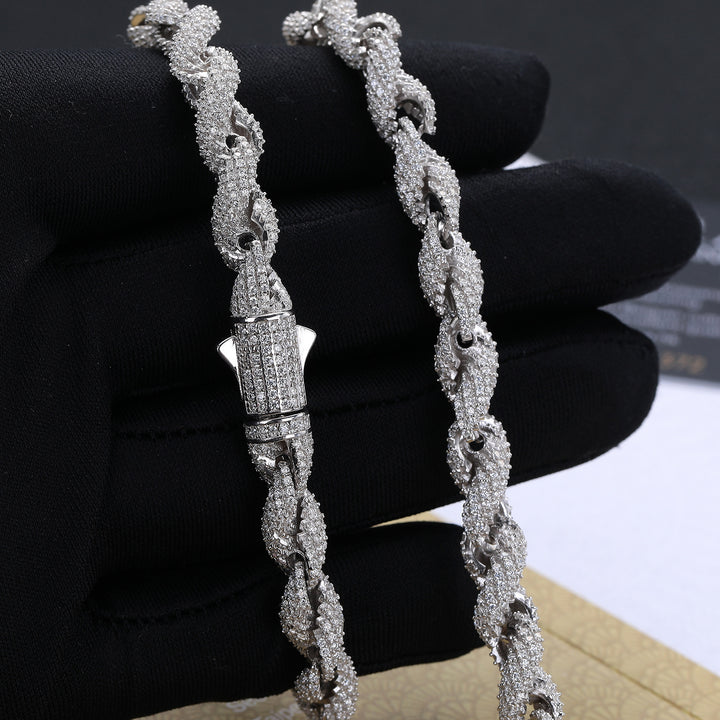Close view of silver-tone rope links and a closed box clasp held against a black glove