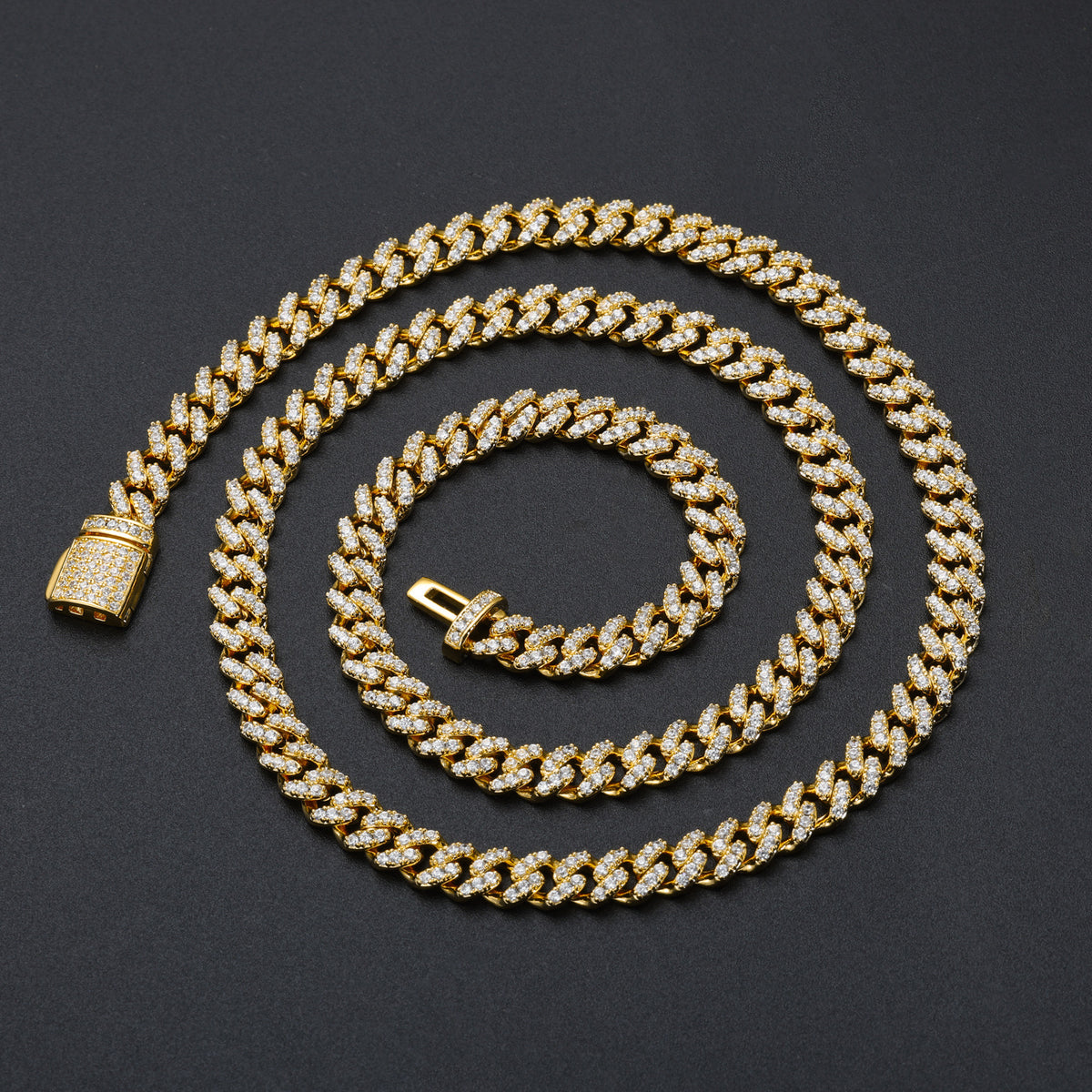Gold-tone moissanite Cuban chain arranged in a wide spiral on black
