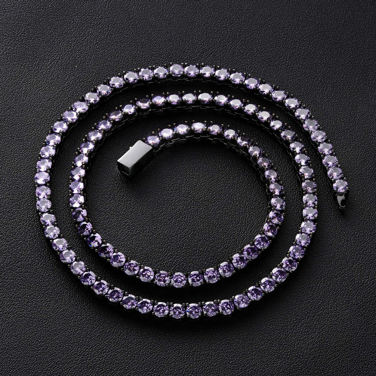 Dark-tone purple-stone tennis necklace arranged in a spiral on black
