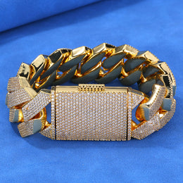 Gold-tone iced Cuban bracelet showing polished inner links on blue fabric