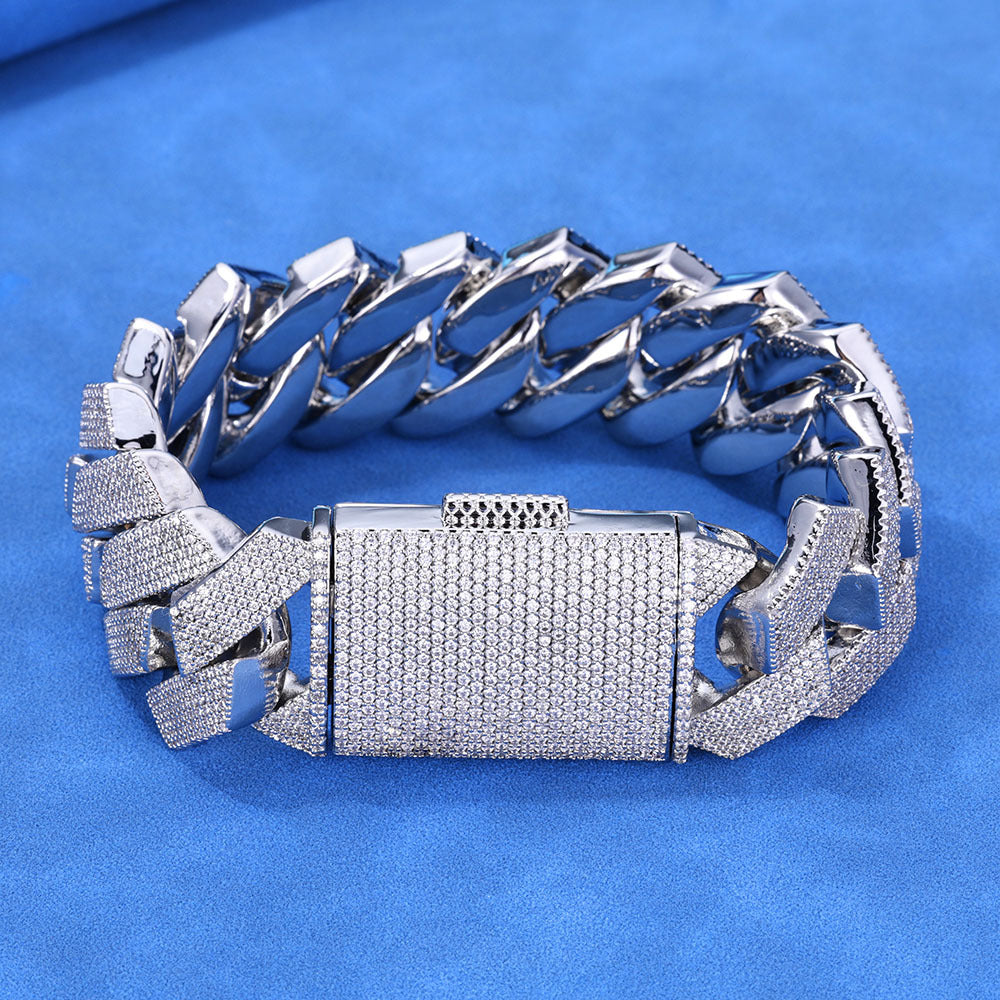 Silver-tone iced Cuban bracelet showing polished inner links on blue fabric