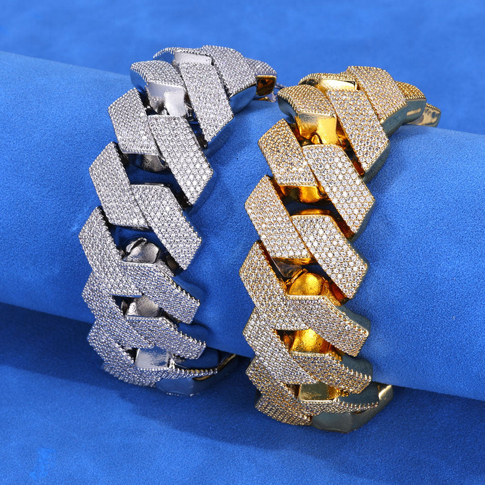 Silver-tone and gold-tone iced Cuban bracelets standing on blue fabric
