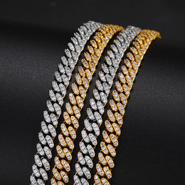 Silver-tone and gold-tone moissanite Cuban links laid side by side on black fabric