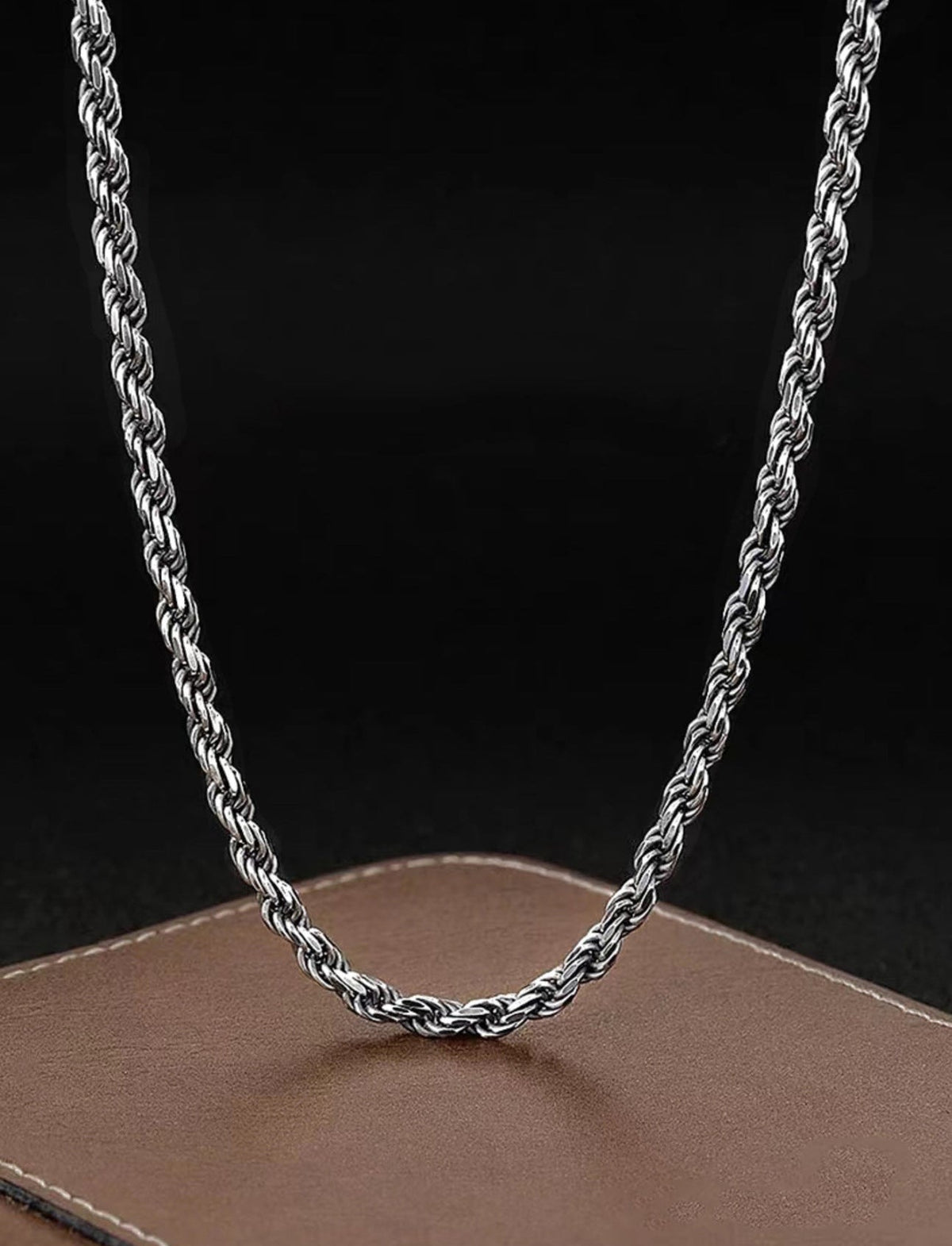 Silver-tone rope chain hanging on a black display bust
