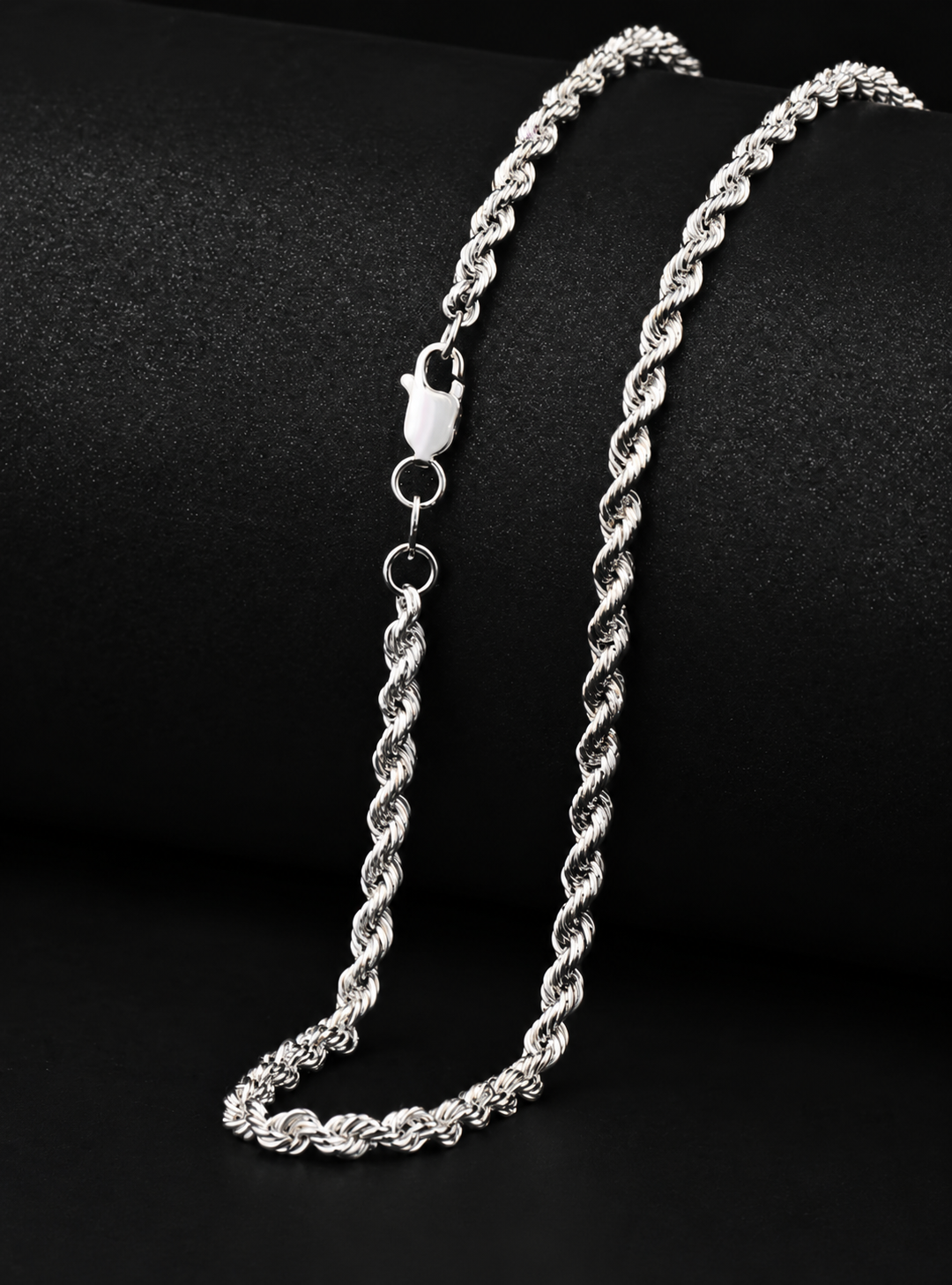 Silver-tone rope chain showing its lobster clasp and connecting rings on black fabric