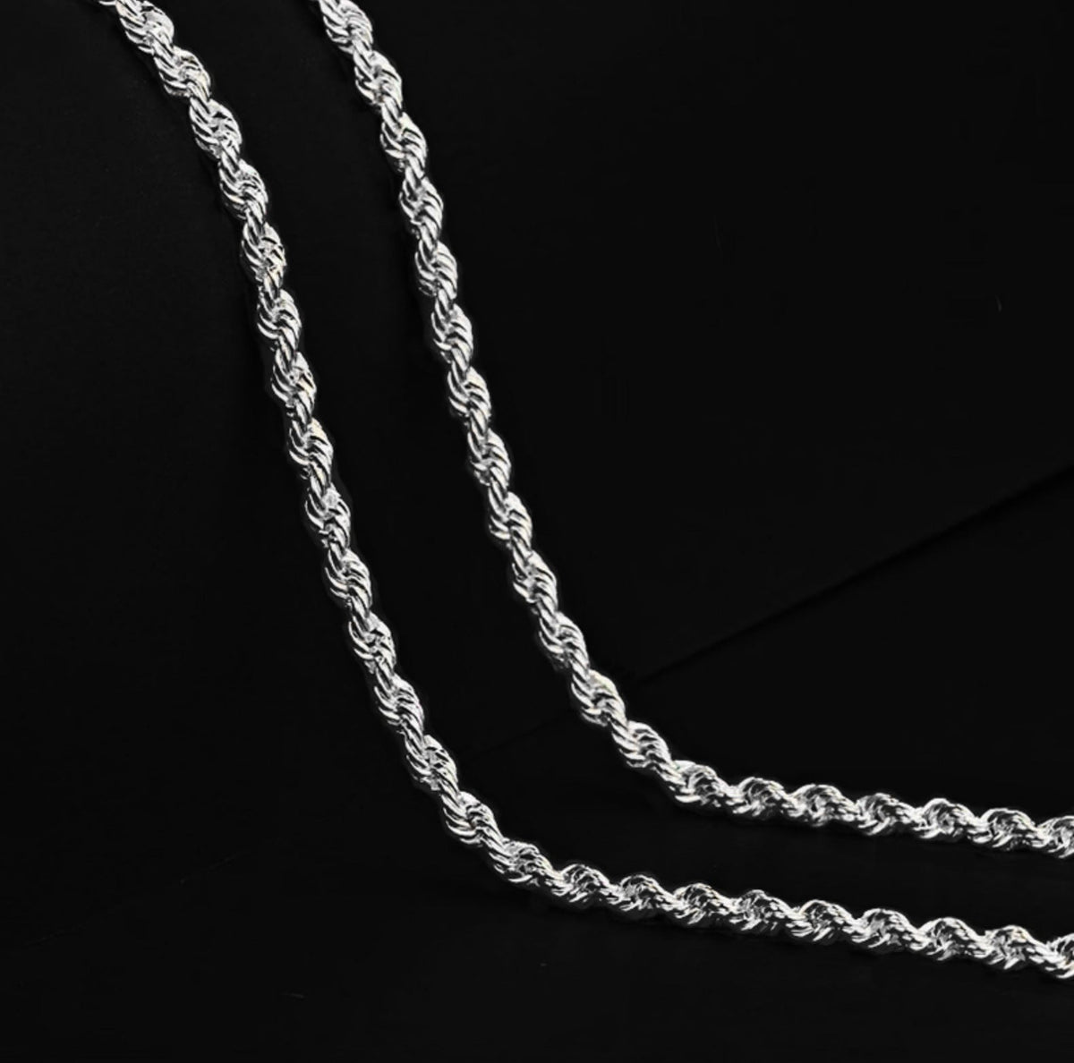 Close-up of two silver-tone rope chain strands on black