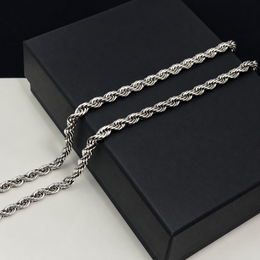 Close-up of a silver-tone rope chain draped on an unbranded black box