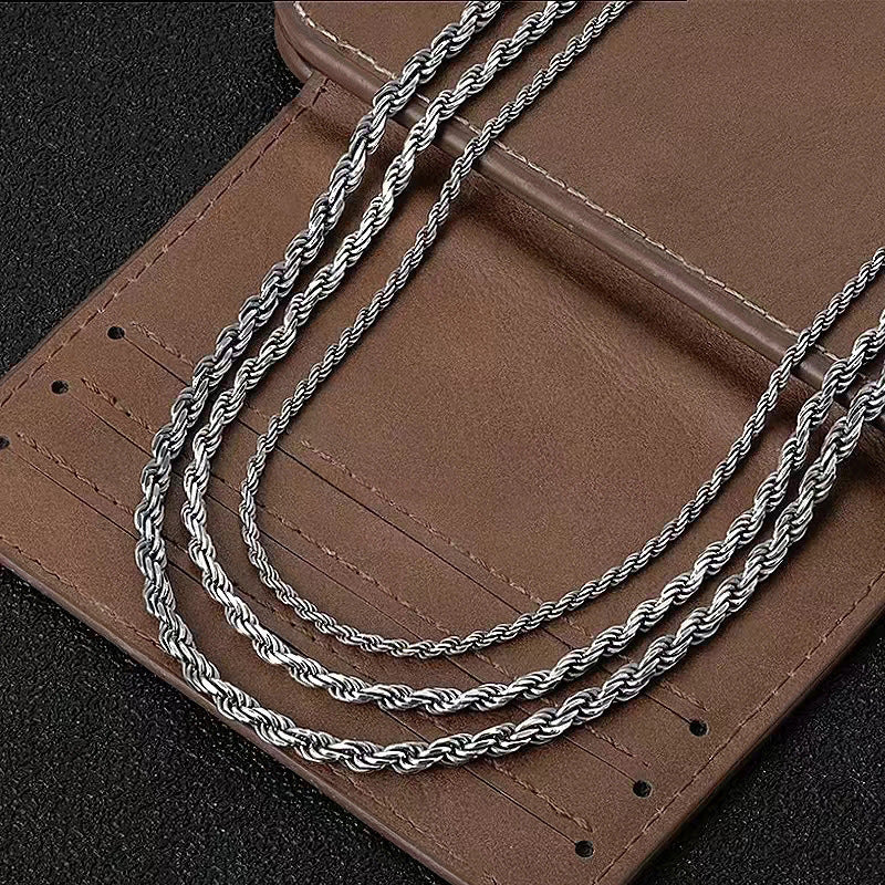 Silver-tone rope chains draped across a brown leather surface