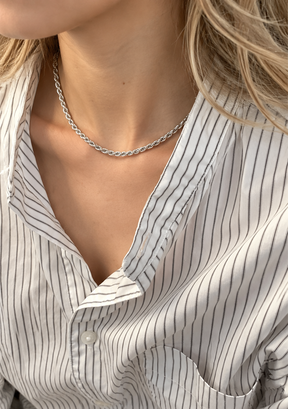 Model wearing a silver-tone rope chain with an open striped shirt