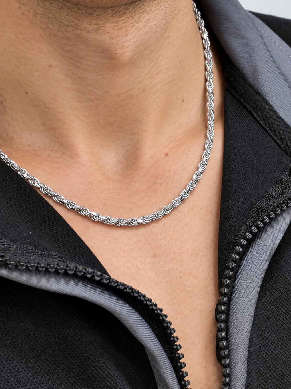 Close-up of a silver-tone rope chain worn with a black zip collar