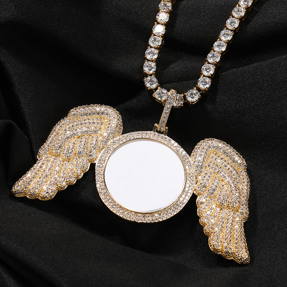 Gold-tone angel wings photo pendant resting on black fabric