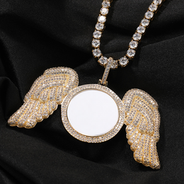 Gold-tone angel wings photo pendant resting on black fabric