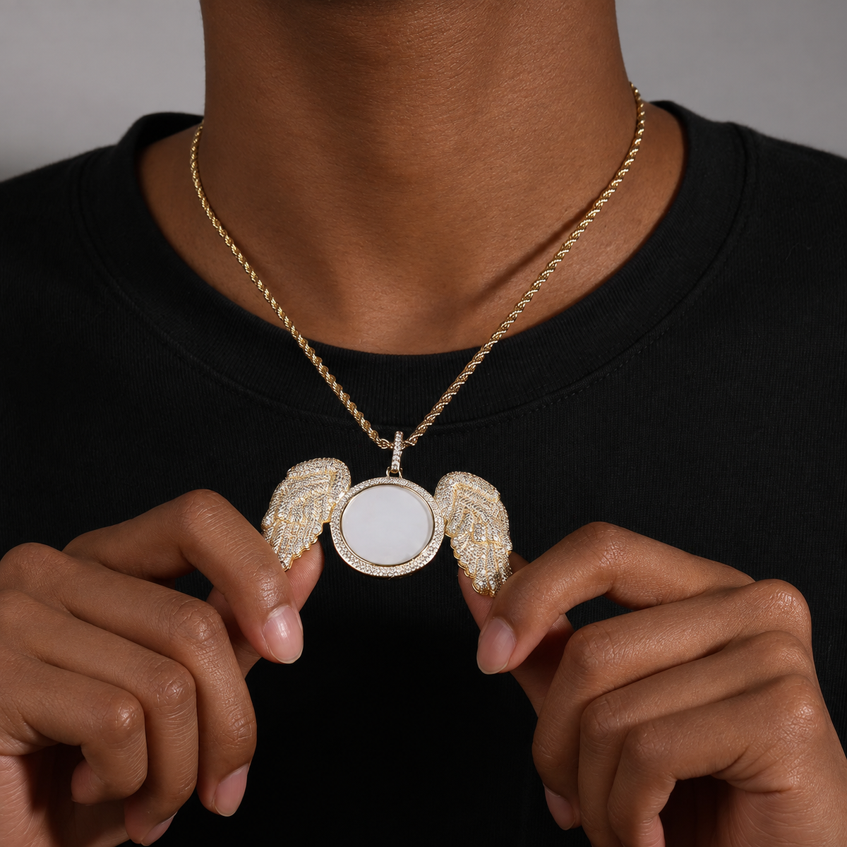 Close view of a gold-tone angel wings photo pendant held at the chest