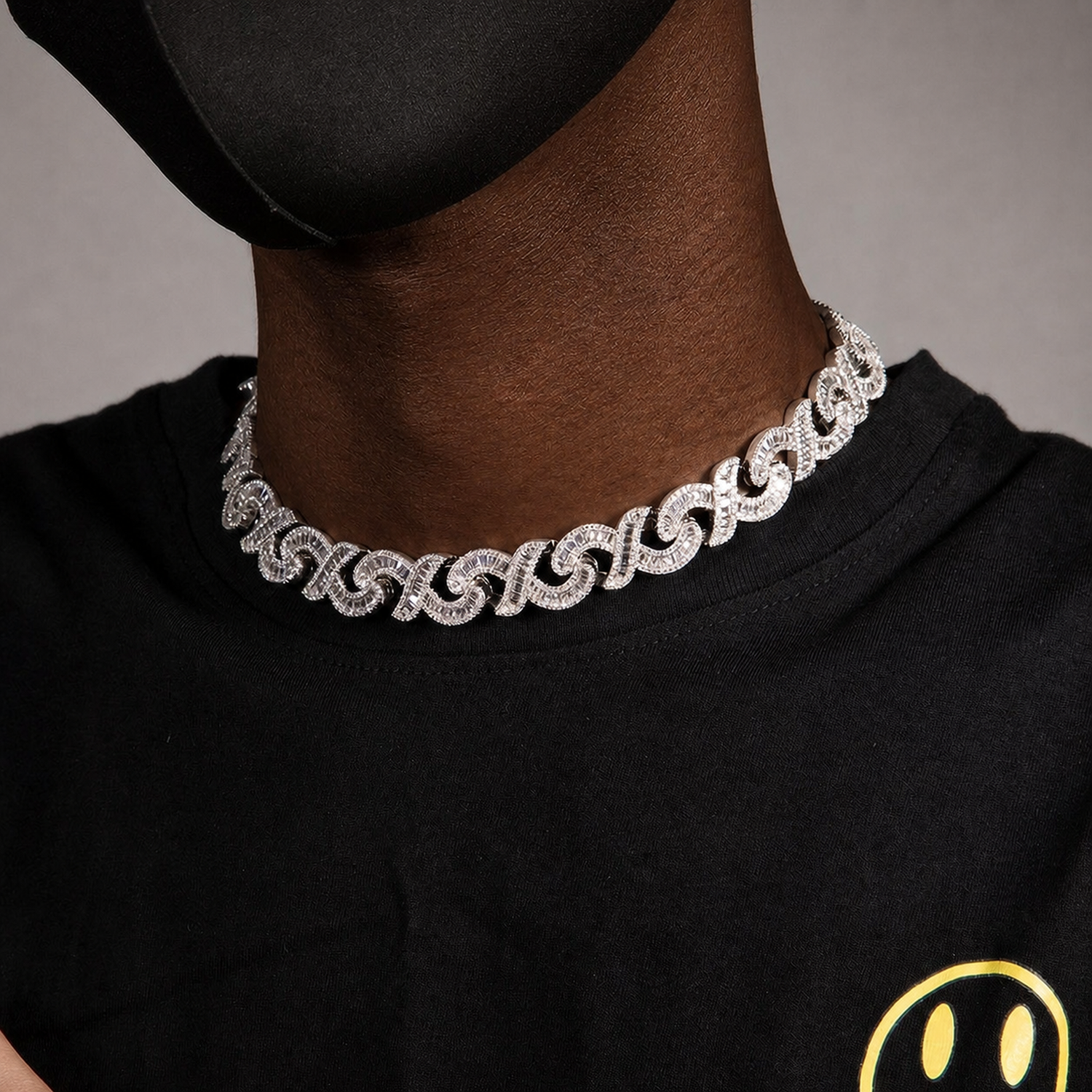 Silver infinity link necklace worn by a deep-brown model at an angle