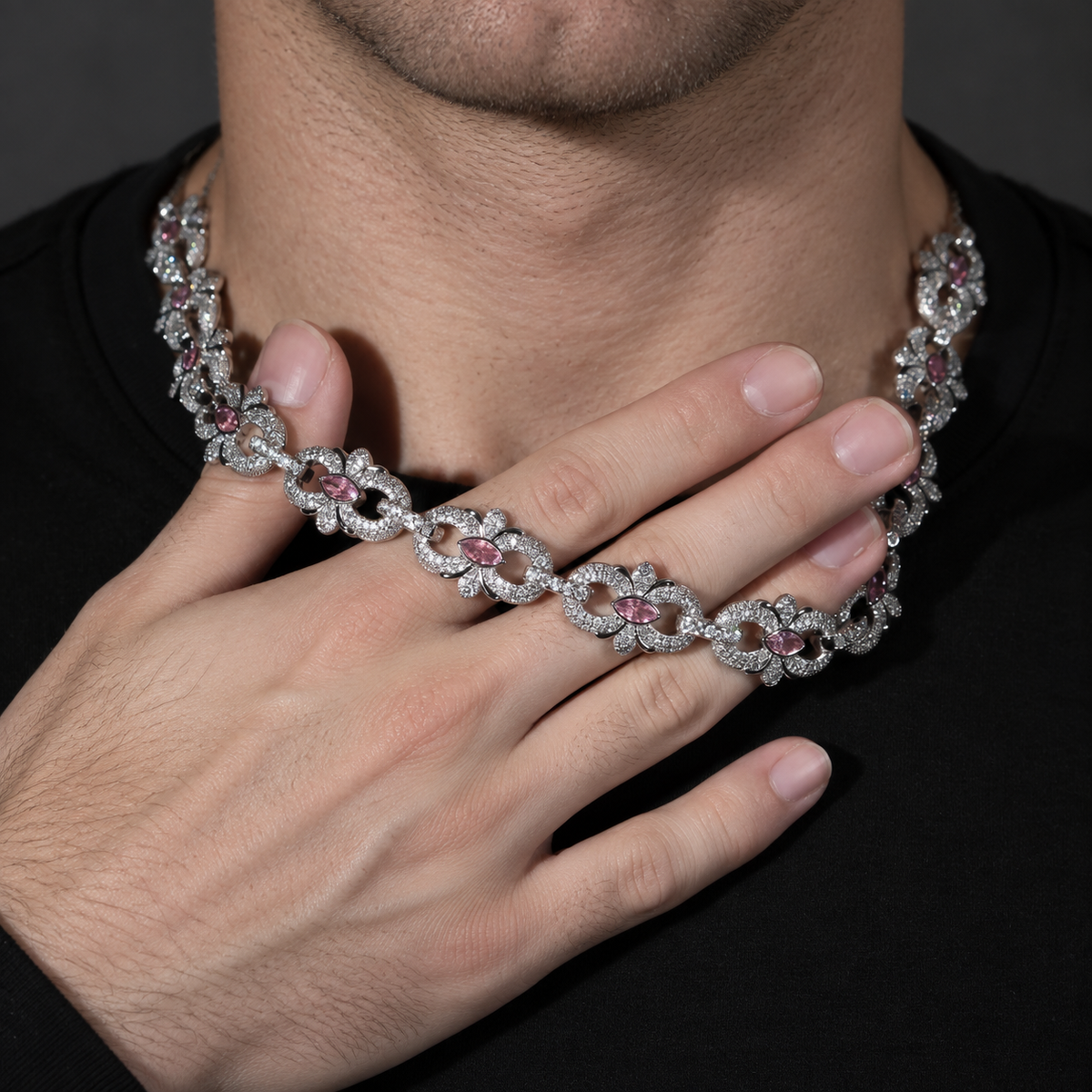 Pink marquise floral link necklace resting across a hand at the neckline of a black shirt