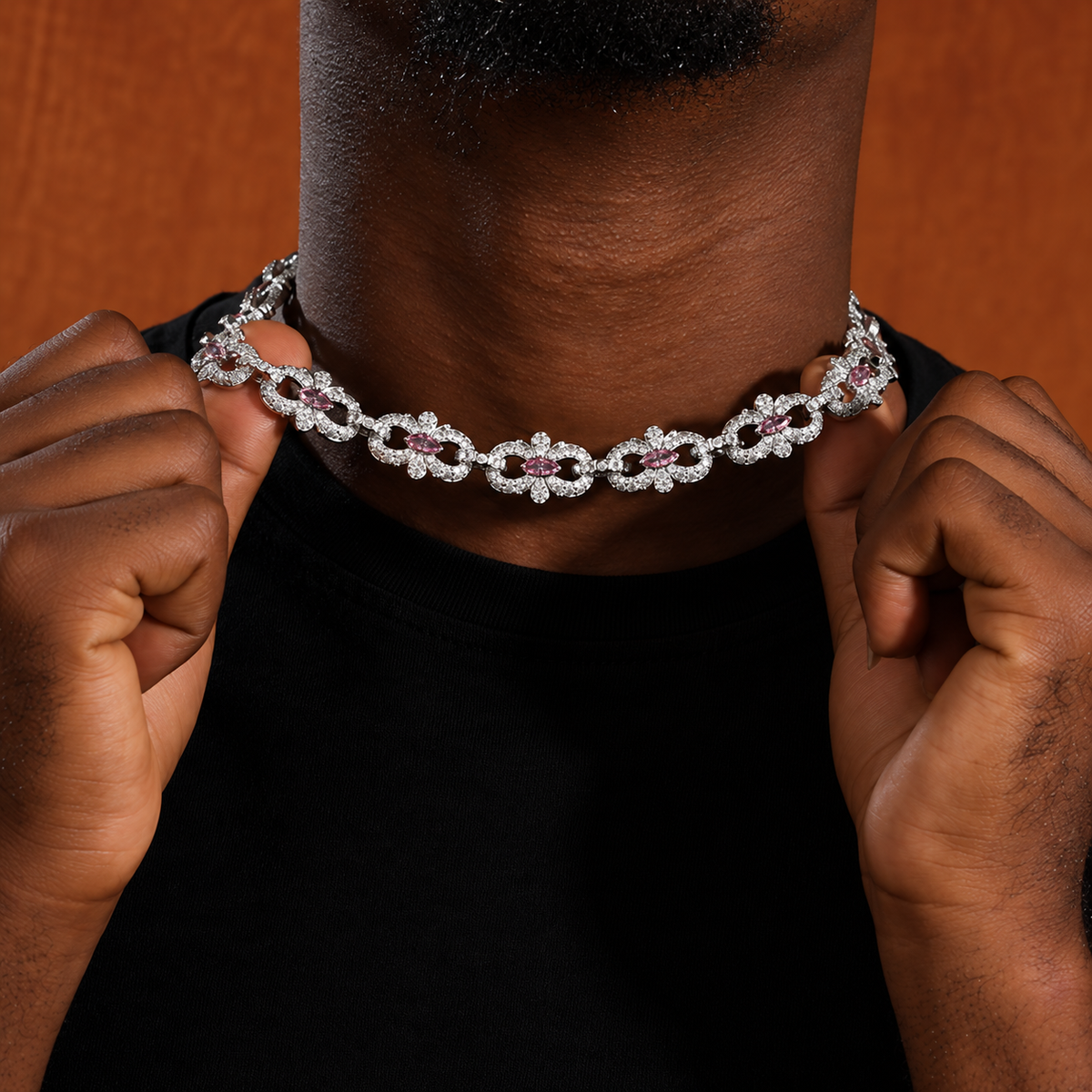 Model holding a pink marquise floral link necklace near the collar with both hands