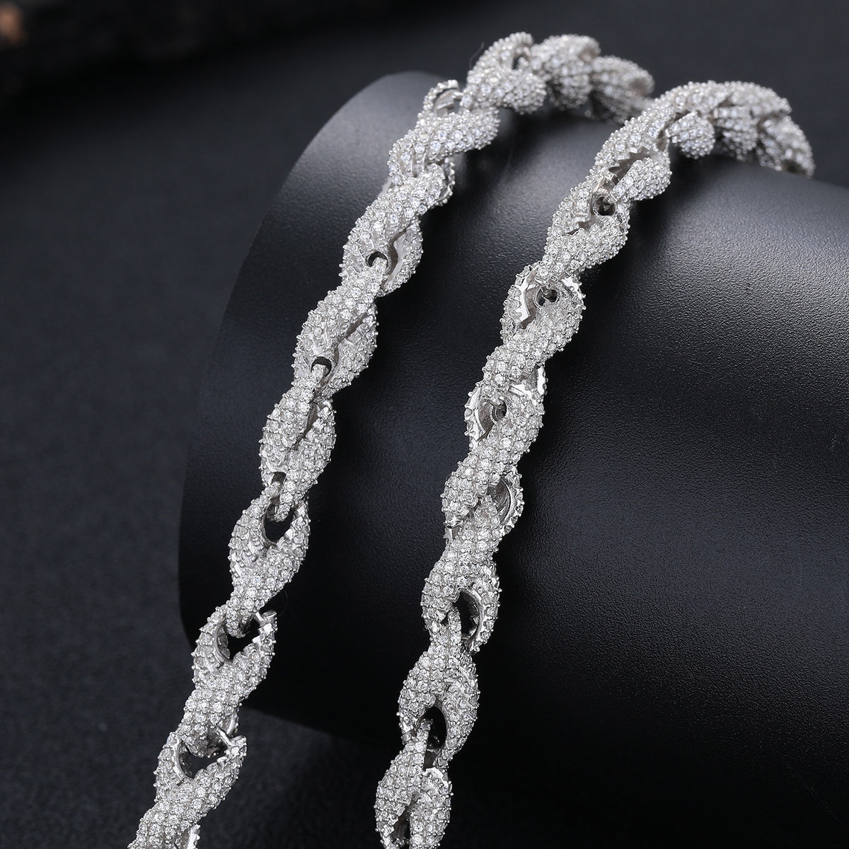 Close view of twisted stone-set rope links draped across a dark display cushion