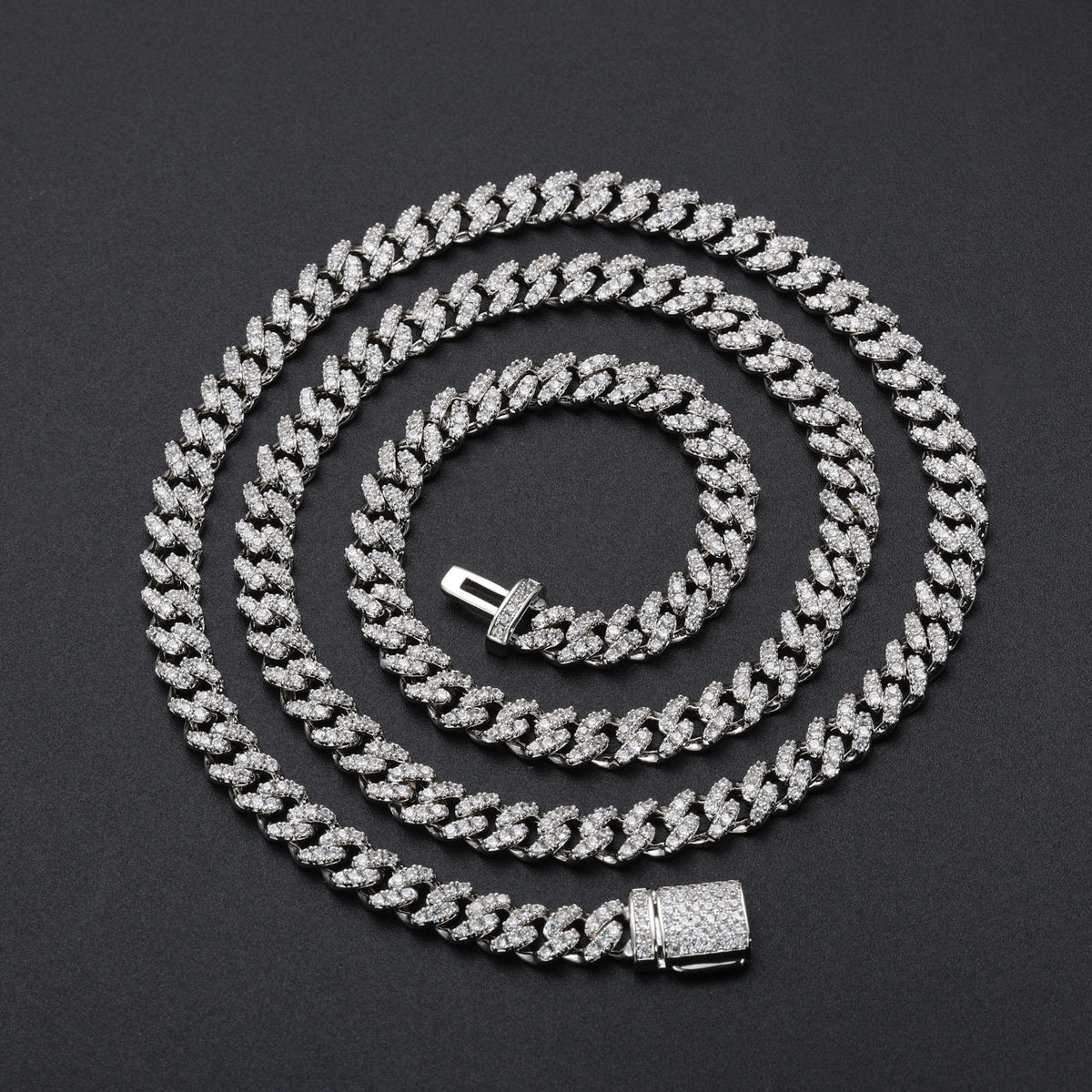 Silver-tone moissanite Cuban chain arranged in a wide spiral on black