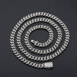 Silver-tone moissanite Cuban chain arranged in a wide spiral on black