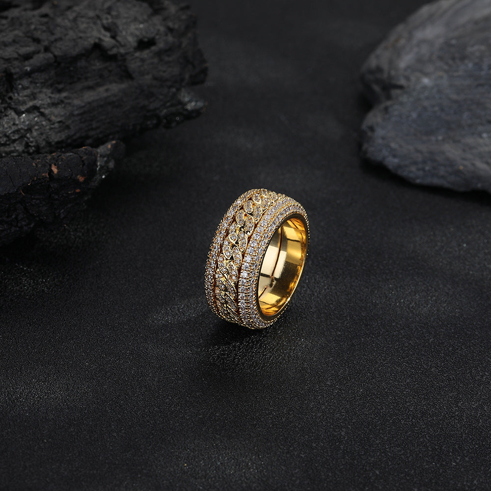 Gold-tone Cuban link ring standing against a dark rock