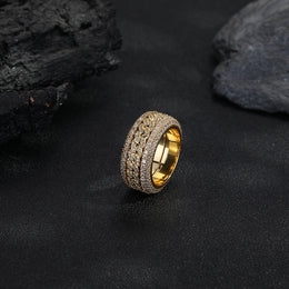 Gold-tone Cuban link ring standing against a dark rock