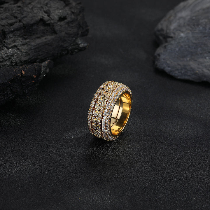 Gold-tone Cuban link ring standing against a dark rock