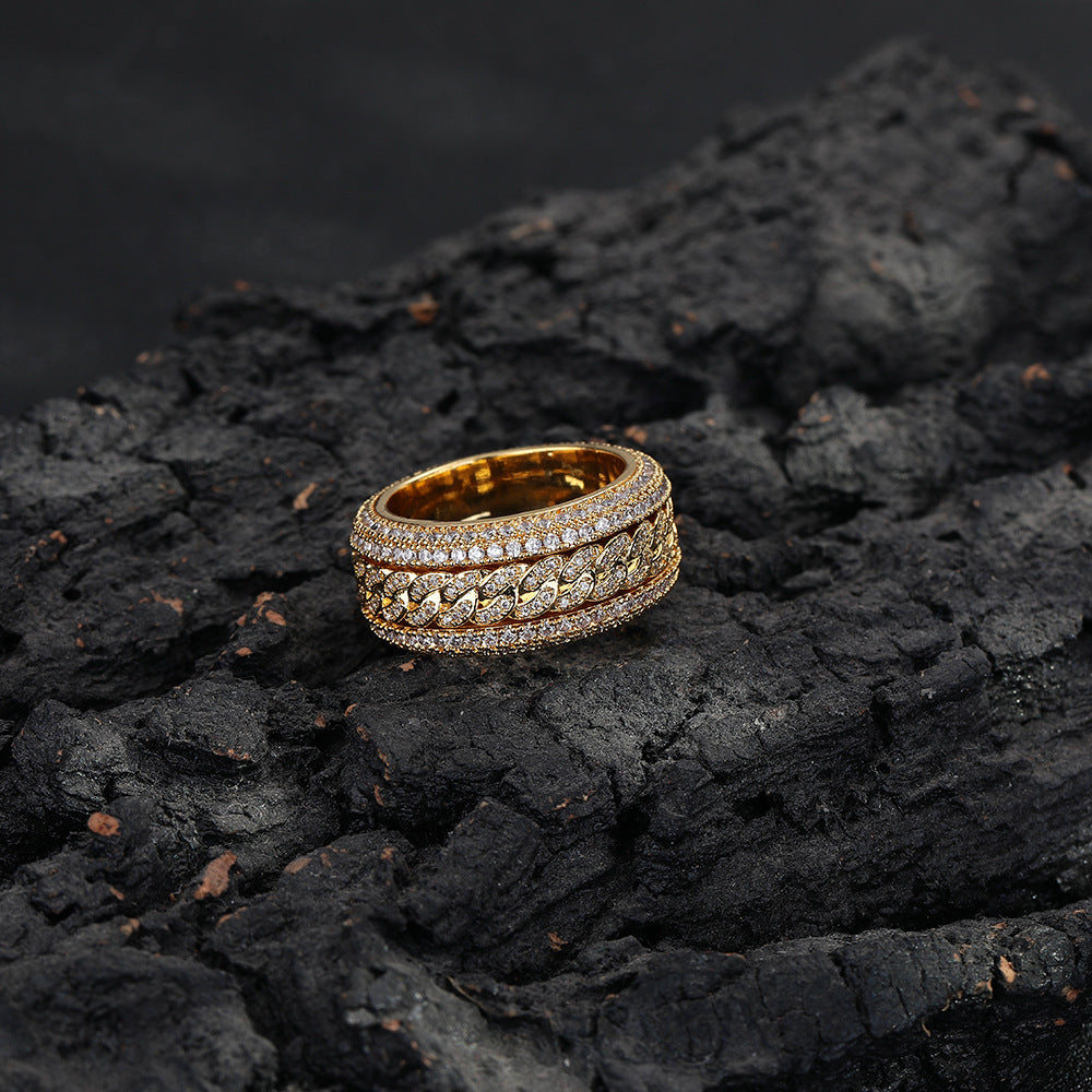 Gold-tone Cuban link ring lying on textured dark rock