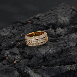 Gold-tone Cuban link ring lying on textured dark rock