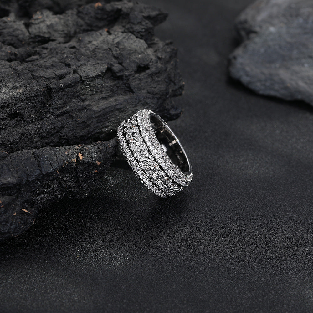 Silver-tone Cuban link ring resting at an angle against dark rocks