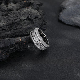 Silver-tone Cuban link ring resting at an angle against dark rocks