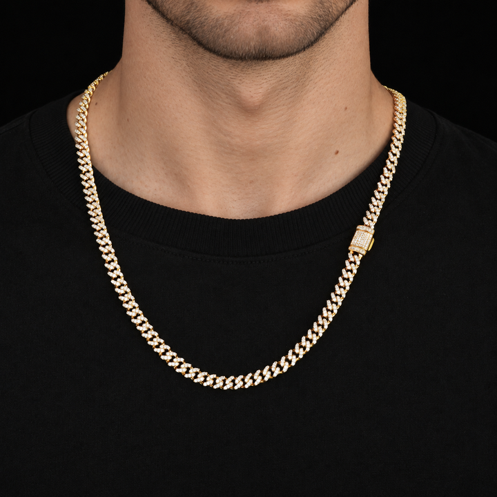 Model wearing a gold-tone moissanite Cuban chain with a side box clasp over a black shirt