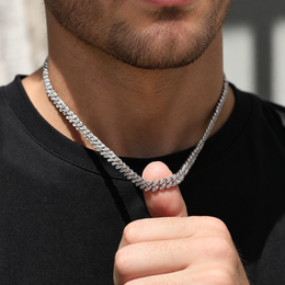 Model lifting a silver-tone moissanite Cuban chain with a thumb over a black shirt