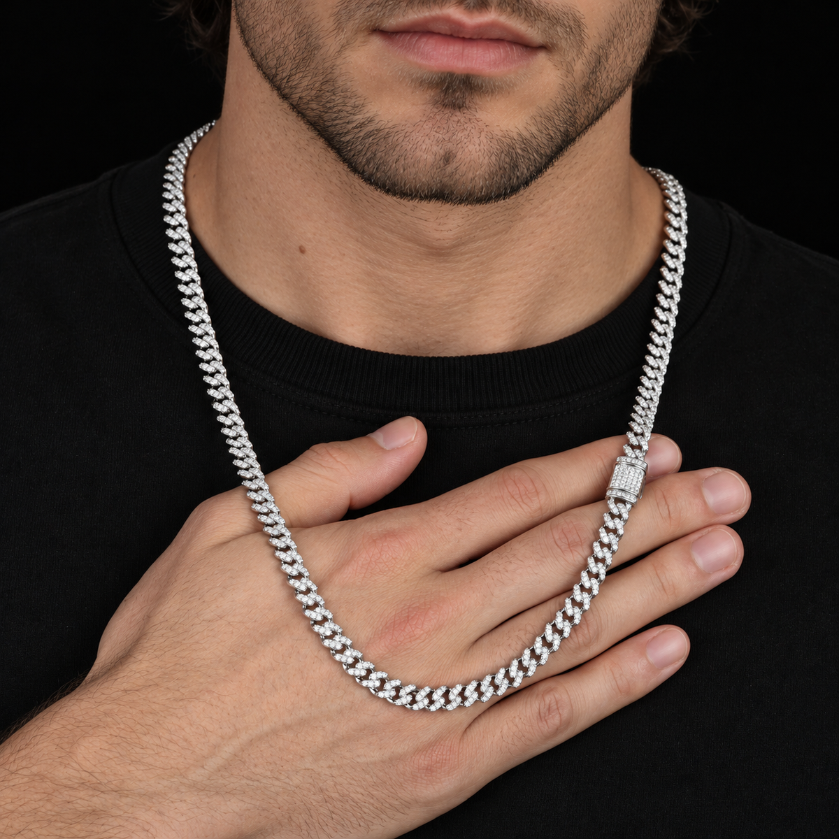 Model holding a silver-tone moissanite Cuban chain across a hand, with the clasp visible