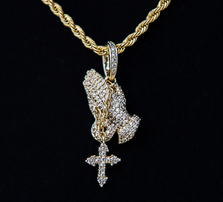 Gold-tone praying hands pendant with a hanging cross displayed on a rope chain