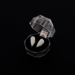 White vampire fang pair in an open box on a dark background