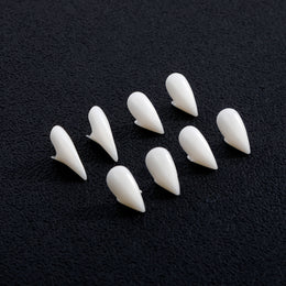 Four pairs of white vampire fangs compared on a dark background
